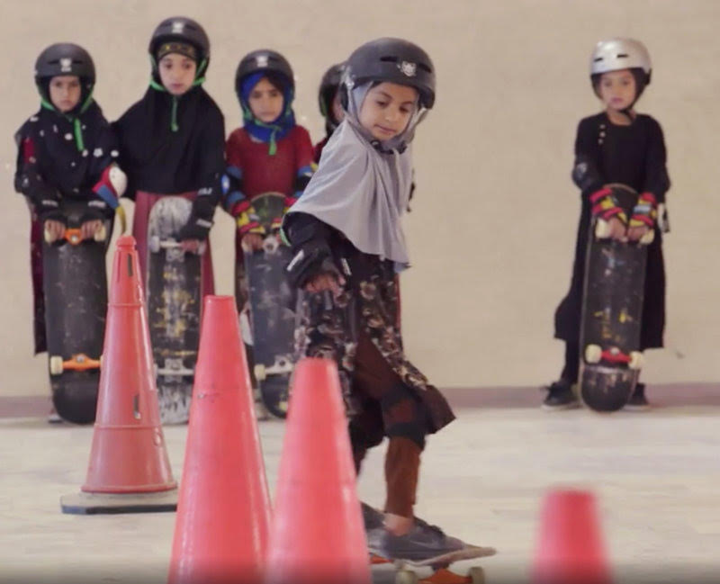 Students wearing headscarves and helmets learn to navigate traffic cones in a scene from the Oscar-winning documentary, "Learning to Skateboard in a Warzone (If You're a Girl)." A&E IndieFilms/ Screenshot by NPR