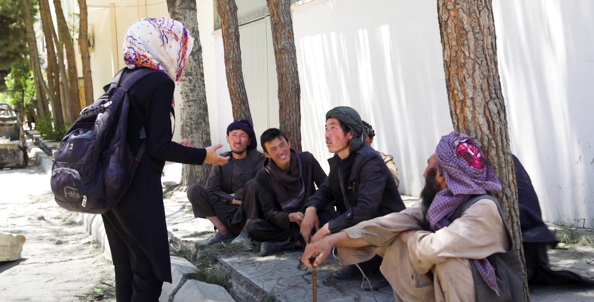 An Afghan woman journalist conducts an interview with bystanders.