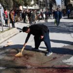 A resident washes a road after gunmen killed two female judges working for the Supreme Court in the capital [Wakil Kohsar/AFP]