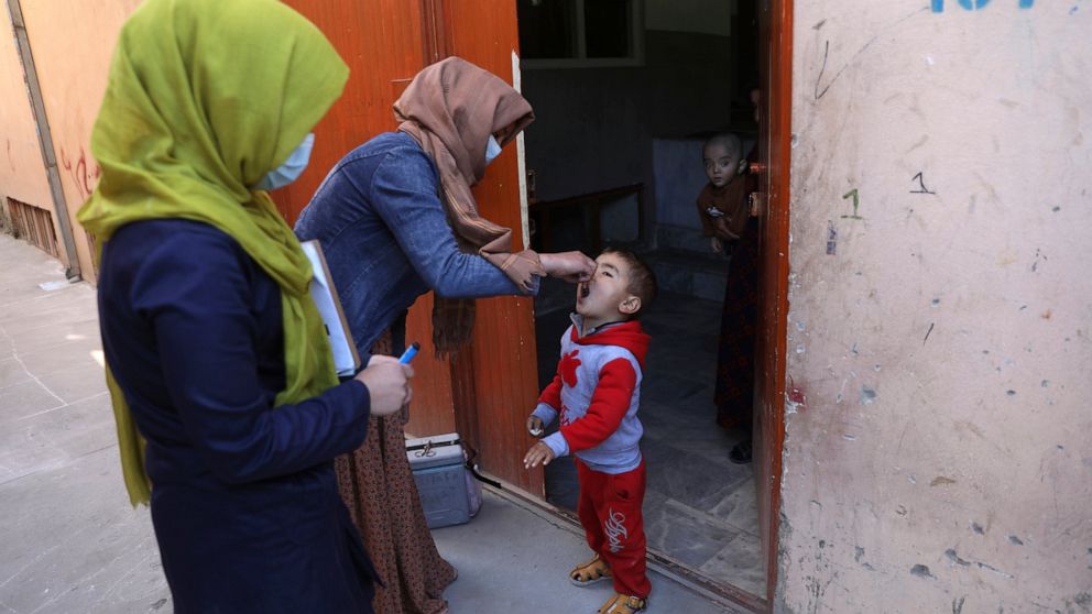 The Associated Press - Health workers administer a polio vaccine to a child during a polio vaccination campaign.
