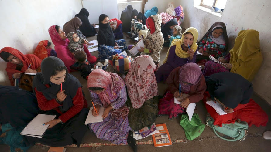 Internally displaced Afghan girls and women study at a class near their temporary homes on the outskirts of Kabul.