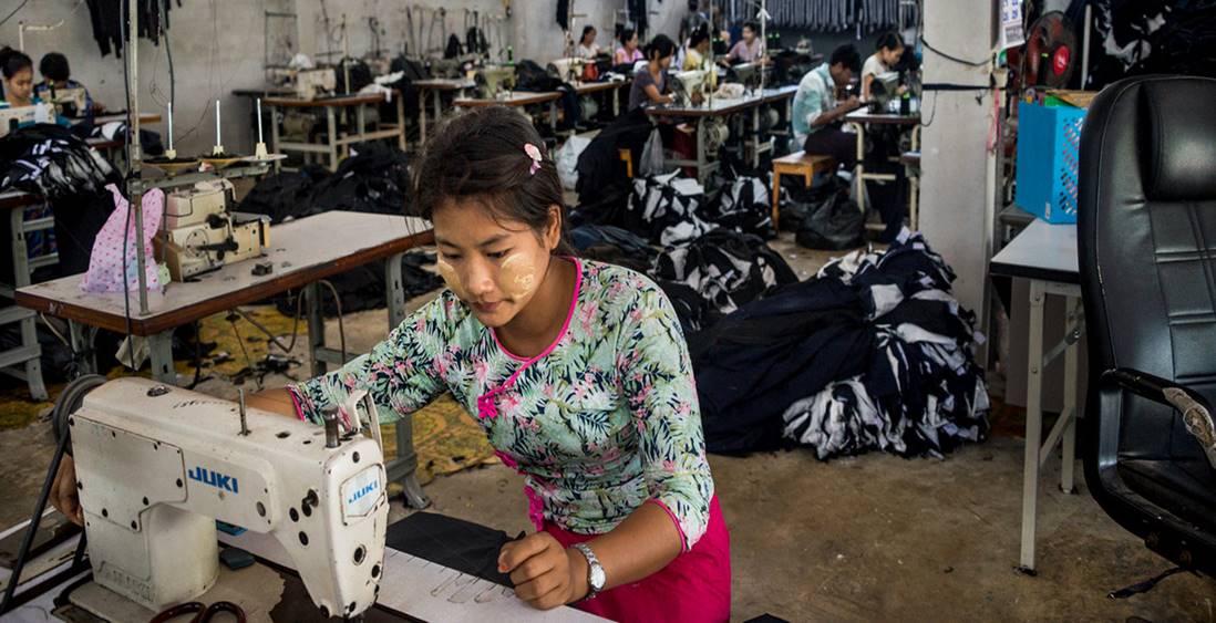 UN Women/Piyavit Thongsa-Ard - A migrant worker sews clothes in a factory in western Thailand. Working more than 12 hours a day, with overtime, they earn less than the minimum daily wage, leaving them with barely enough money for rent, food, or savings.