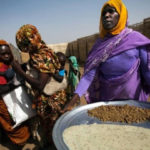 A woman prepares a tray with lentils and cereals at a food distribution center in Tawilla, North Darfur, Sudan. Photo by: Albert Gonzalez Farran / UNAMID / CC BY-NC-ND