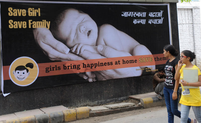 Young Indian women walk past a billboard in New Delhi encouraging the birth of girls - Raveendran/AFP/Getty