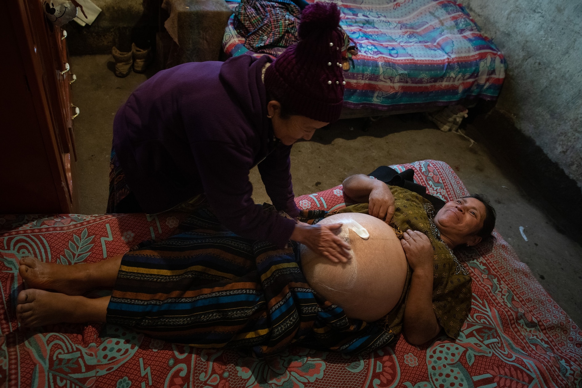 Midwife Epifania Elías Gonzales examines Delfina Vicente López inside Vicente’s home on a remote hilltop not far from San Carlos Sija, Guatemala. During her 30-year career, Elías has helped hundreds of women in her predominantly K’iche' speaking Indigenous dialogue.