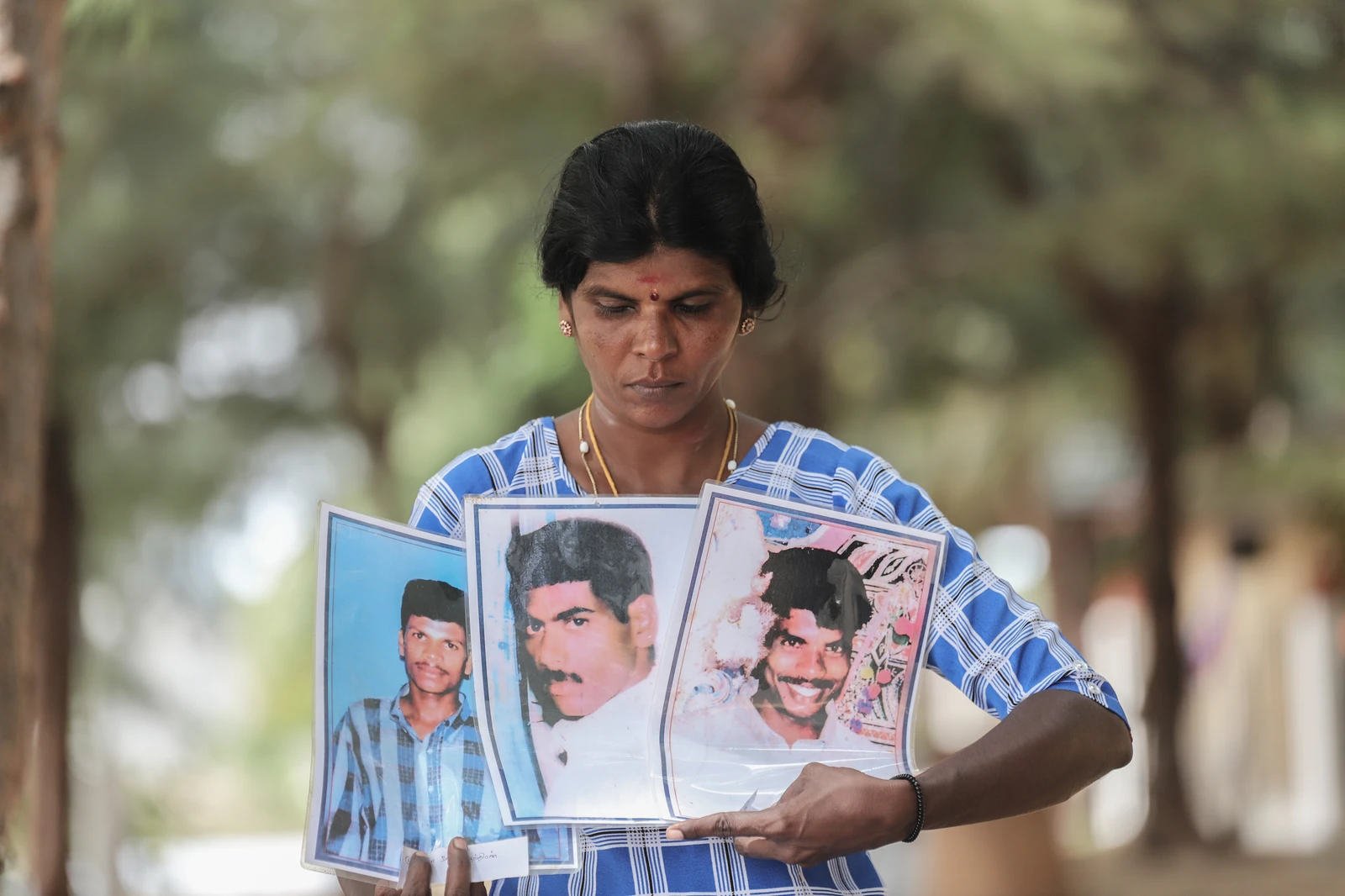 RANJANIDEVI HOLDS PHOTOS OF HER HUSBAND (MIDDLE) AND HER TWO BROTHERS WHO WENT MISSING DURING THE CIVIL WAR.