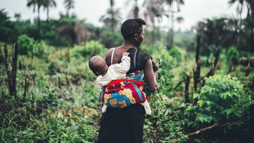 A young woman in Sierra Leone carries her child on her back © Annie Spratt