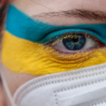 A woman wears face paint in the colors of the Ukrainian flag while protesting against the Russian invasion of Ukraine in front of Brandenburg Gate in Berlin on Feb. 24. HANNIBAL HANSCHKE/GETTY IMAGES