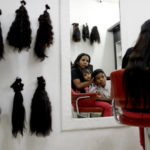 Nelly Navarro sits with her kids Nerianny and Luis in a beauty salon where she came to consult how much money she could get for her hair, in Caracas, Venezuela, Tuesday, April 2, 2019. Navarro said she needs the $100 to travel to Colombia where she's planning to move. (AP Photo/Natacha Pisarenko)